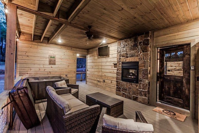 interior space with wood walls, ceiling fan, a fireplace, light hardwood / wood-style floors, and wood ceiling