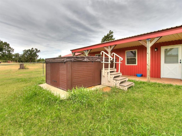 back of house featuring a yard and a hot tub