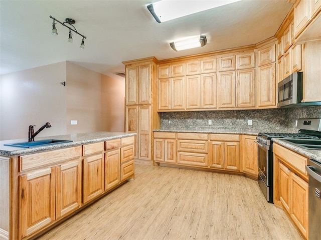 kitchen featuring backsplash, sink, light hardwood / wood-style floors, and appliances with stainless steel finishes