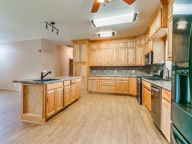 kitchen featuring light wood-type flooring, backsplash, stainless steel appliances, sink, and a center island