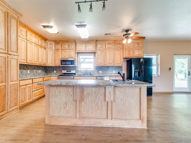 kitchen featuring light brown cabinetry, stainless steel appliances, light hardwood / wood-style floors, and an island with sink