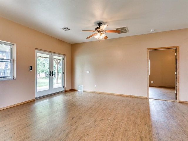 empty room with french doors, light wood-type flooring, and ceiling fan