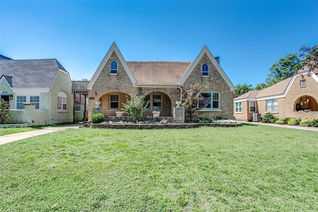 english style home featuring central AC unit and a front yard