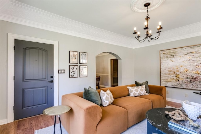 living room with wood-type flooring, ornamental molding, and a chandelier