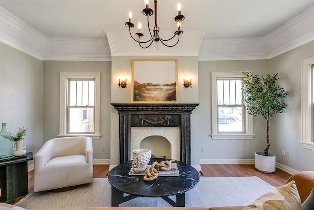 sitting room with hardwood / wood-style floors, ornamental molding, and an inviting chandelier