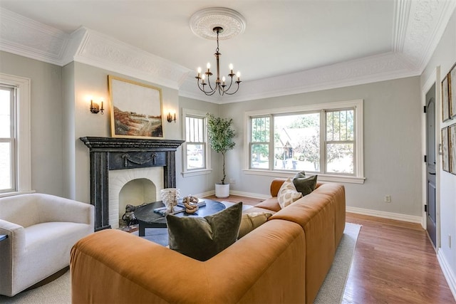 living room with a fireplace, an inviting chandelier, ornamental molding, and hardwood / wood-style flooring