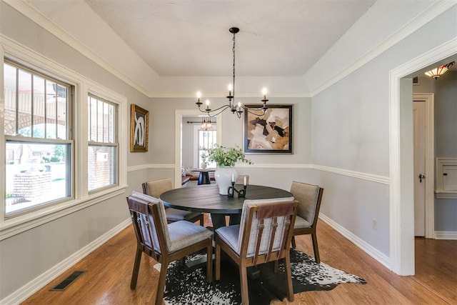 dining room featuring crown molding, light hardwood / wood-style flooring, and a notable chandelier