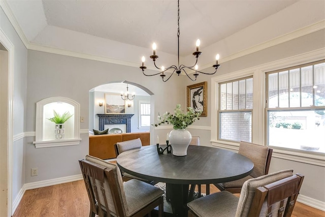 dining area with ornamental molding, light hardwood / wood-style floors, a raised ceiling, and a notable chandelier