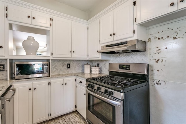 kitchen with ventilation hood, white cabinets, light stone counters, and appliances with stainless steel finishes