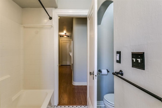 bathroom featuring toilet, wood-type flooring, and tiled shower / bath