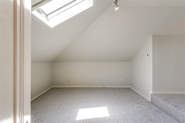 additional living space featuring carpet flooring and lofted ceiling with skylight