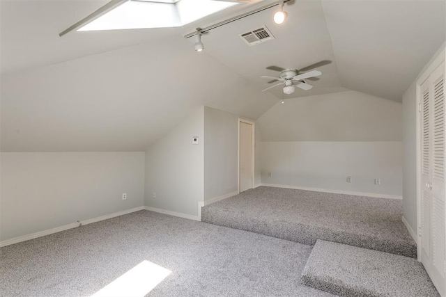 additional living space with carpet floors, ceiling fan, and vaulted ceiling with skylight