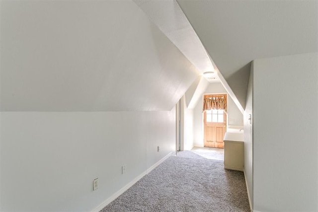 additional living space featuring light colored carpet and vaulted ceiling