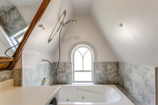 bathroom with vanity, a bath, and vaulted ceiling