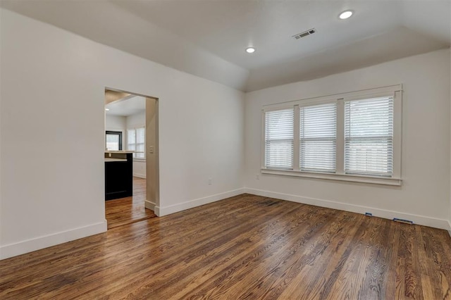 spare room featuring lofted ceiling and dark hardwood / wood-style floors