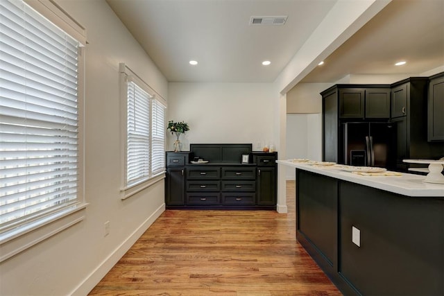 kitchen featuring black fridge with ice dispenser and light hardwood / wood-style flooring