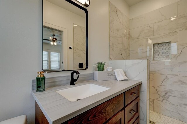 bathroom with a tile shower, ceiling fan, and vanity