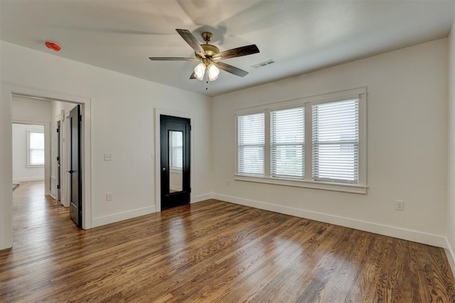 empty room with ceiling fan and dark hardwood / wood-style flooring