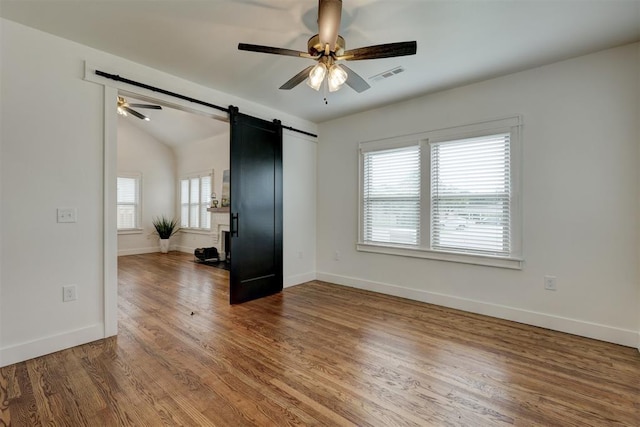 empty room with a barn door, hardwood / wood-style flooring, and a wealth of natural light