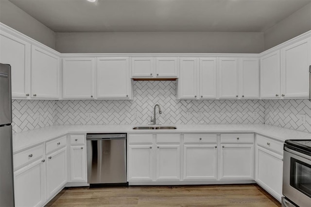 kitchen with sink, white cabinets, stainless steel appliances, and light hardwood / wood-style flooring