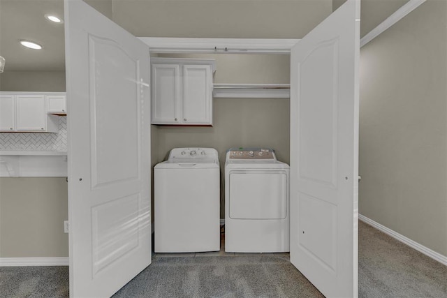 clothes washing area with washer and clothes dryer, carpet floors, and cabinets