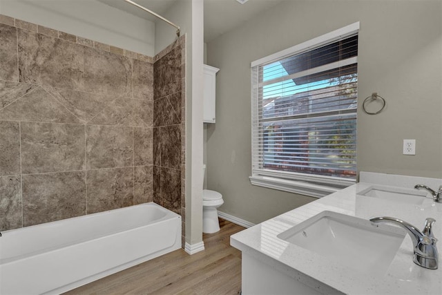 full bathroom with hardwood / wood-style floors, vanity, toilet, and tiled shower / bath