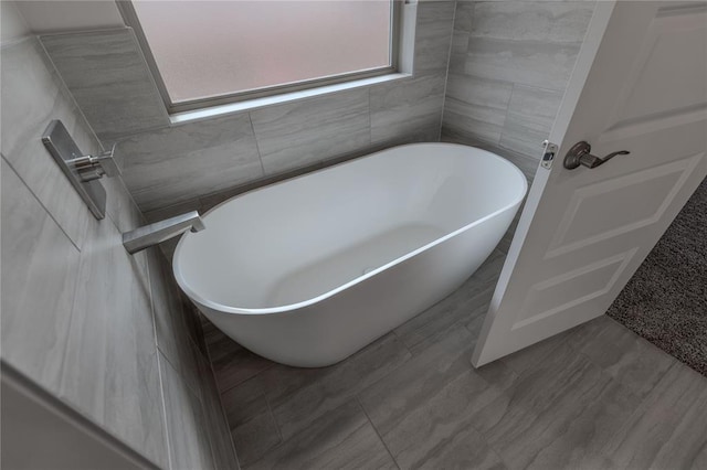 bathroom featuring a bathtub and tile walls