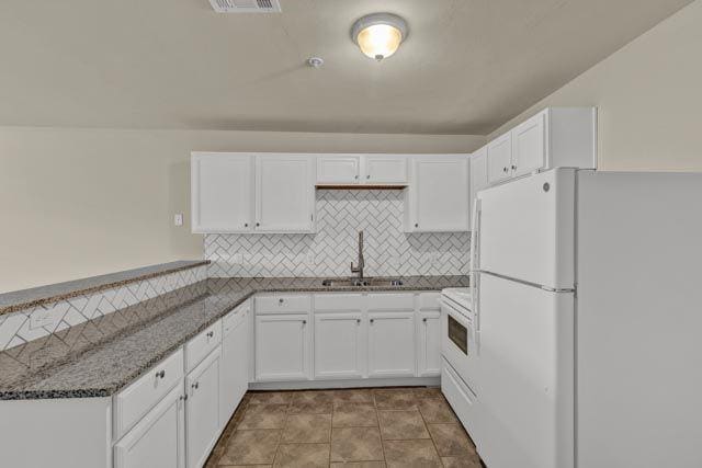 kitchen featuring tasteful backsplash, white appliances, sink, dark stone countertops, and white cabinets