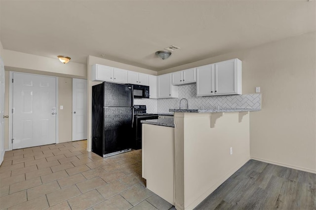 kitchen with white cabinetry, backsplash, kitchen peninsula, black appliances, and light wood-type flooring