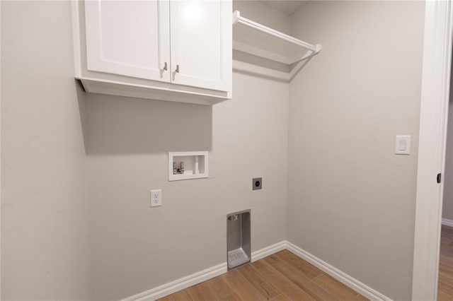 clothes washing area featuring electric dryer hookup, hookup for a washing machine, light hardwood / wood-style flooring, and cabinets