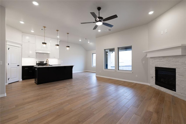 living room featuring lofted ceiling, sink, light wood-type flooring, ceiling fan, and a fireplace