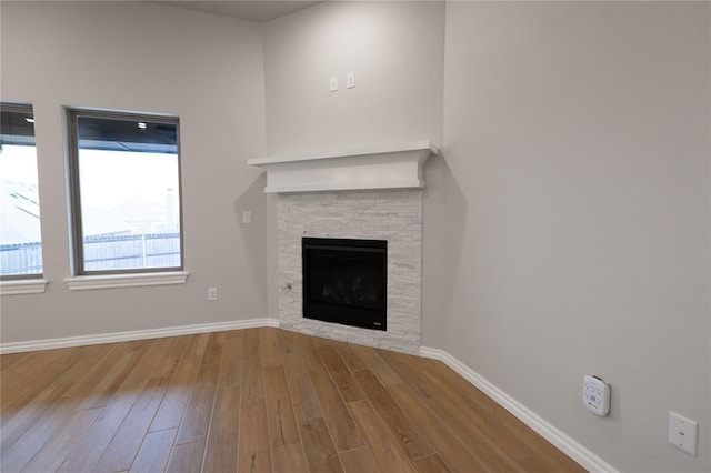 unfurnished living room featuring a stone fireplace and light hardwood / wood-style floors