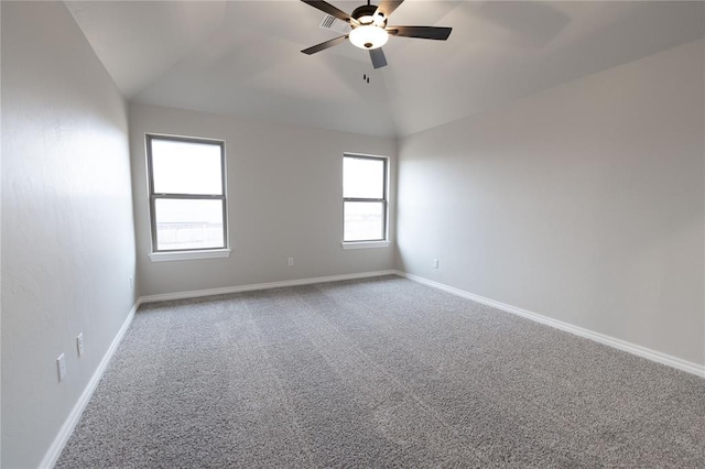 carpeted empty room with a wealth of natural light, ceiling fan, and vaulted ceiling