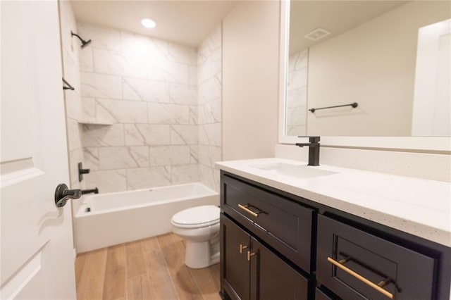 full bathroom featuring vanity, tiled shower / bath combo, wood-type flooring, and toilet