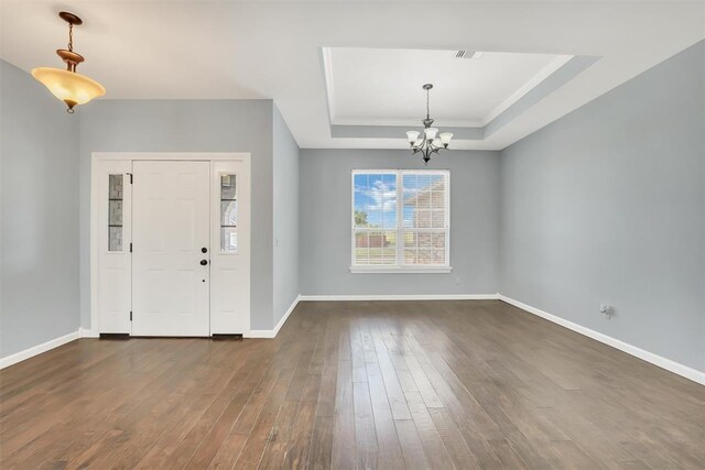 entryway with a chandelier, a tray ceiling, dark hardwood / wood-style floors, and crown molding