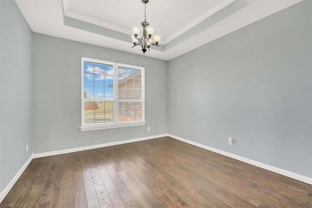 unfurnished room featuring a chandelier, dark hardwood / wood-style flooring, and a raised ceiling