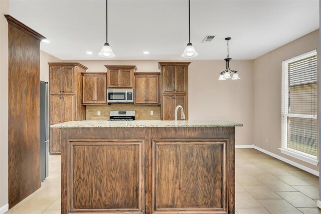 kitchen featuring decorative backsplash, a center island with sink, pendant lighting, and appliances with stainless steel finishes