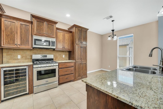 kitchen featuring pendant lighting, sink, wine cooler, appliances with stainless steel finishes, and a chandelier