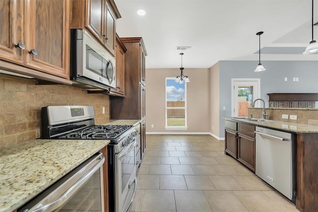 kitchen featuring appliances with stainless steel finishes, backsplash, decorative light fixtures, and sink