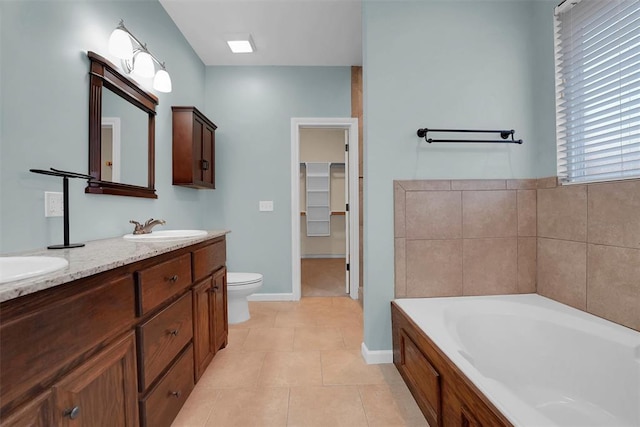 bathroom featuring tile patterned flooring, a bath, vanity, and toilet