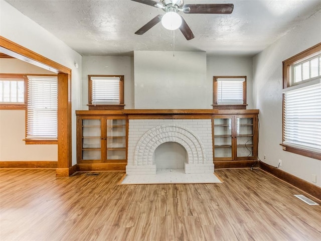 unfurnished living room with a fireplace, hardwood / wood-style floors, a textured ceiling, and a healthy amount of sunlight