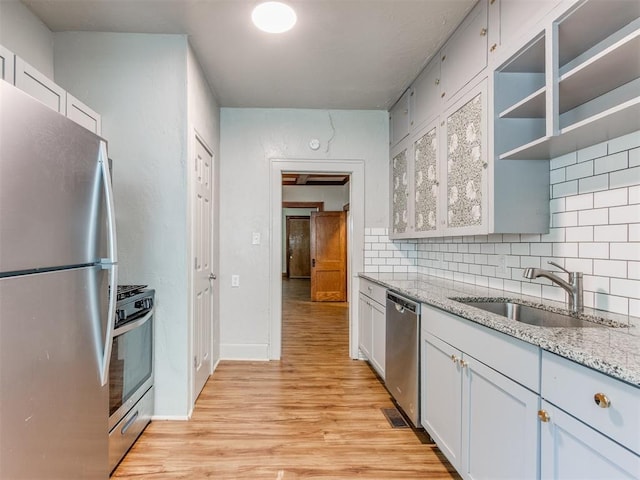 kitchen featuring backsplash, white cabinets, sink, light hardwood / wood-style flooring, and stainless steel appliances