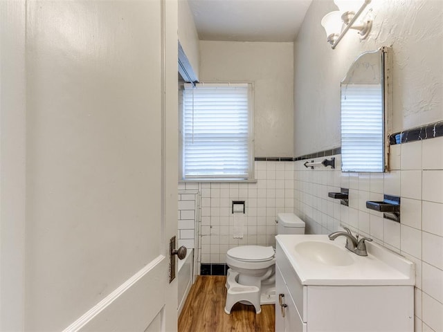 bathroom with hardwood / wood-style floors, vanity, toilet, and tile walls