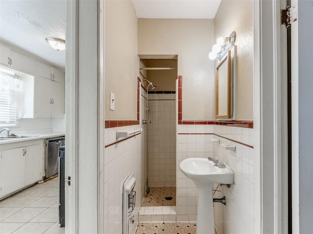 bathroom with a tile shower, tile patterned flooring, tile walls, and sink