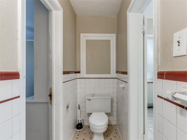 bathroom featuring tile patterned flooring, tile walls, and toilet