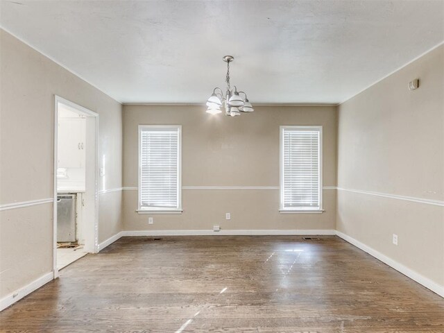 spare room with hardwood / wood-style flooring and a notable chandelier