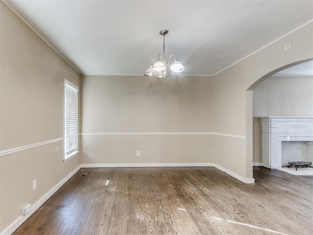 spare room with wood-type flooring and an inviting chandelier