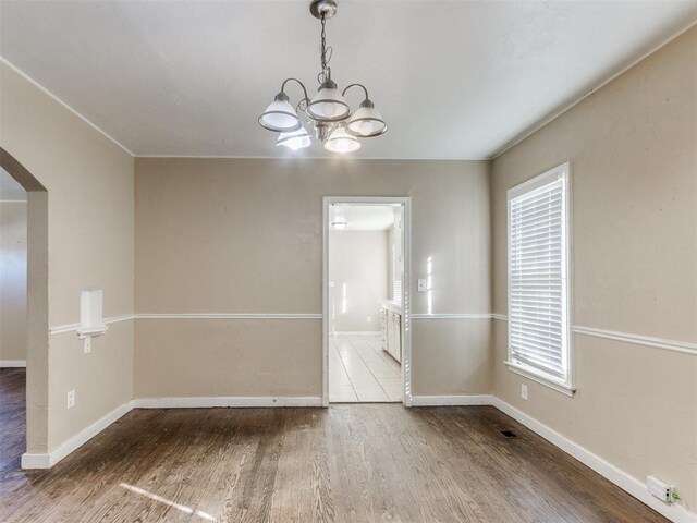 empty room with hardwood / wood-style floors and a chandelier