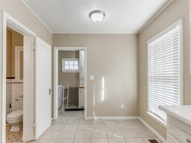 interior space with light tile patterned floors, ensuite bathroom, and tile walls