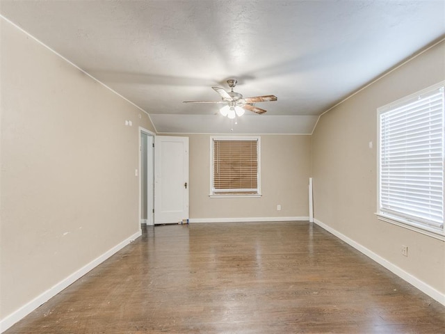 empty room featuring a wealth of natural light, ceiling fan, wood-type flooring, and lofted ceiling